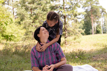40-year-old mother and her daughter are having fun in park. The beauty of nature, family scenes, outdoor recreation. Summer vacation or weekend getaway. Happy family concept.