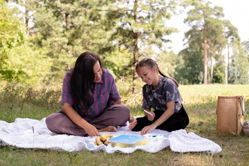 40-year-old mother and her daughter are having fun in park. The beauty of nature, family scenes, outdoor recreation. Summer vacation or weekend getaway. Happy family concept.