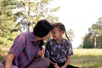 40-year-old mother and her daughter are having fun in park. The beauty of nature, family scenes, outdoor recreation. Summer vacation or weekend getaway. Happy family concept.