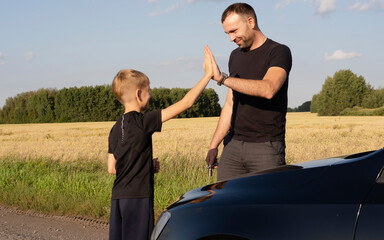 caring father teaches his beloved child how to repair car, explaining and teaching him how to use wrench and tools. They actively communicate while spending time together.
