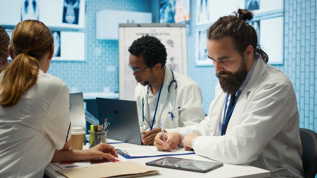 Physician writing a prescription for treatment plan at his cabinet desk, recommending medicine for disease prevention. Medic consulting analytics and hospital records in a clinic. Camera B. - Powered by Adobe