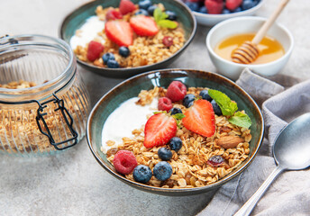 Granola bowls with berries, yogurt, nuts, and honey for breakfast