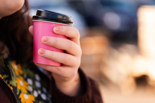 Hands of a woman holding hot coffee cup