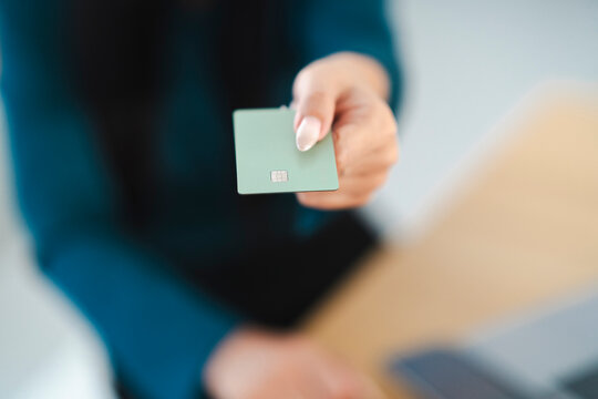 A person holds out a payment card, ready to make a transaction.