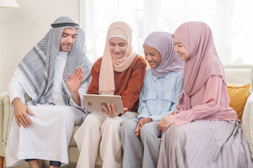 portrait of happy muslim family in traditional clothes sitting on sofa in living room at home,enjoying tablet together,family holiday leisure time