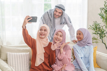 happy muslim family in traditional clothes taking selfie together in the living room