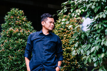 Thoughtful Young Asian Man in Dark Shirt Posing Outdoors