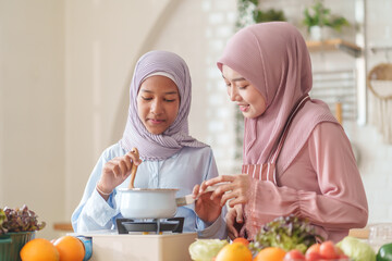 muslim girl with mother in hijab cooking organic vegetables and fruits together in the kitchen