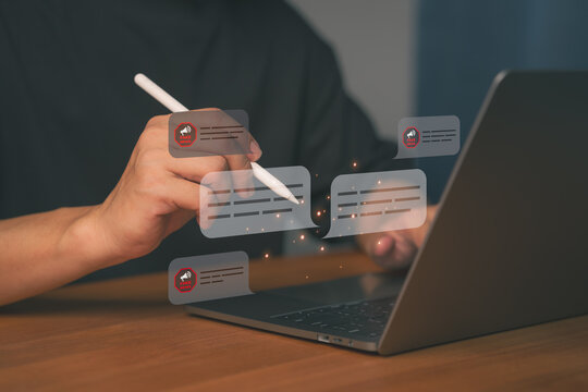 Close-up of hands using a pen on a laptop with floating chat bubbles showing “Fake News” alerts. Concept for misinformation, digital communication, social media fact-check, and online disinformation.