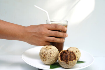 Human Hand Holding Tropical Woodapple Juice on White Background.