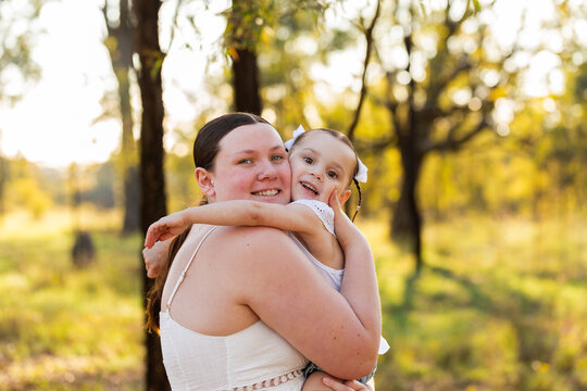 portrait of mother and daughter hugging each other in green country setting