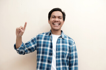 Fototapeta premium Southeast Asian man wearing flannel shirt showing happy excited expression with giving number 12345 by hand gesture, on white isolated background.