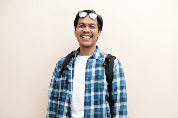 Southeast Asian man wearing cap and carrying backpack standing and smiling expression happy, vacation, holiday.
