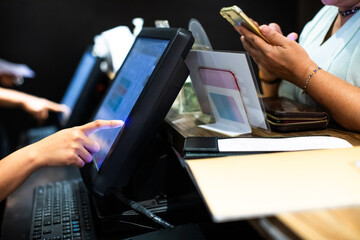 Selective focus to edge of POS machine with blurry cashier staff receive orders from customers at counter service in restaurant or cafe.