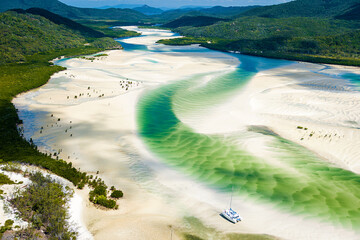 Solitary boat rests in shifting green sands at Whitehaven Beach.