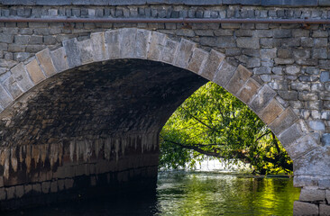 The arch of the old stone bridge over the river in close-up.