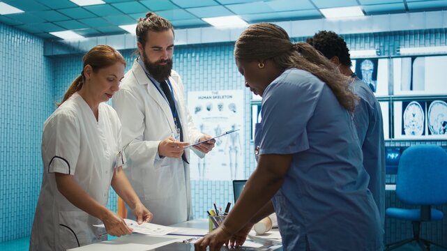 Healthcare team discusses human anatomy and diagnostic strategies in a medical office. Collective work ensures accurate treatment plans and professional solutions, expertise in radiology. Camera B.