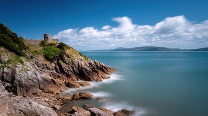 Obraz premium Coastal landscape with historic tower, calm ocean, blurred sky
