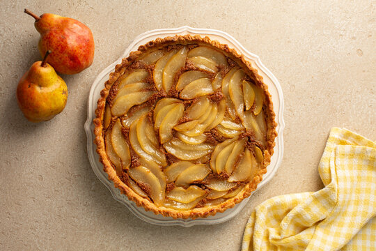 Top view of classic French poached pear tart, made with a sweet frangipane, almond and wallnuts cream. Top view, natural light.