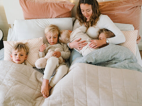 Young boys snuggling with mum on the bed