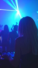 A confident woman stands behind a DJ booth, skillfully mixing tracks with headphones on, surrounded by colorful lights and an energetic crowd dancing.