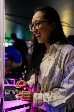 Smiling woman enjoying arcade gaming indoors
