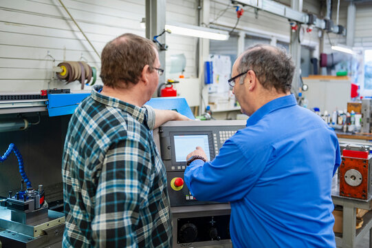 Engineer and supervisor discussing machine operation in production hall