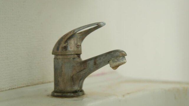 An old, dirty, hard water scaled, dripping or leaking faucet