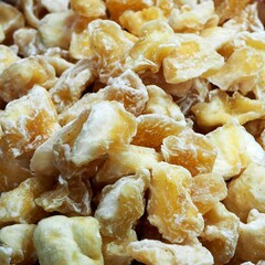 Close-up of golden dried fruits covered in sugar powder, stacked messily. Perfect for food blogs or recipe sites