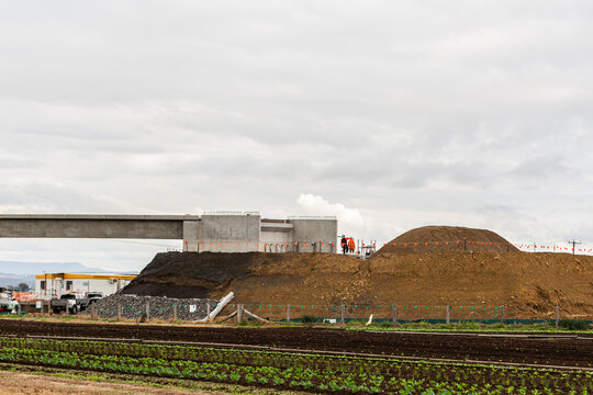 tiny patch of agricultural farmland overshadowed by worksite construction work on infrastructure