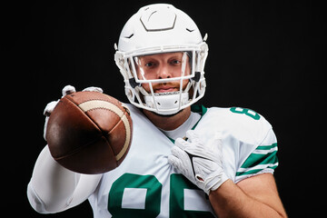Portrait of American football player in white uniform holding football