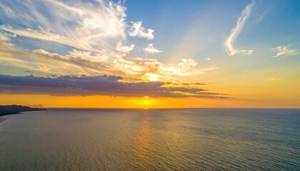 Obraz premium Aerial view of an ocean horizon at sunset, sunbeams burst through clouds