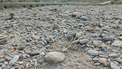 Vast expanse of dry riverbed filled with scattered stones and sand, hinting at nature's power and potential for change.