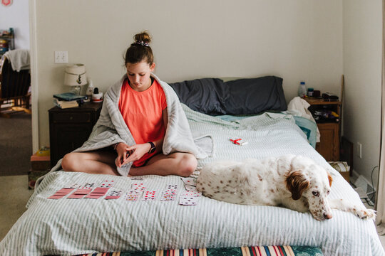 Girl playing solitaire while her dog sleeps next to her