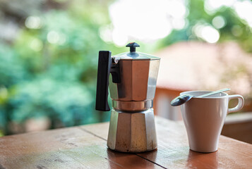 Coffee maker and coffee cup on a table with a forest background