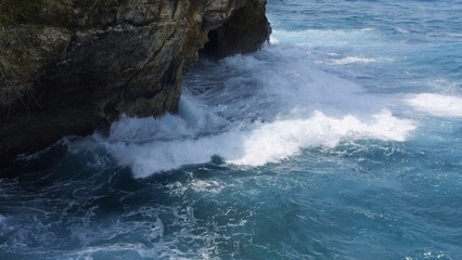 Powerful ocean waves crash against coastal rocks under bright sunlight Ocean energy shows balance between strength and calm symbol of nature resilience and harmony within endless ocean motion
