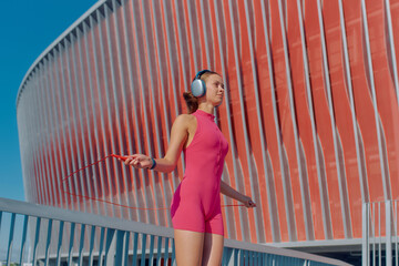 Skipping rope exercise by a woman in sportswear during bright daylight near a modern building