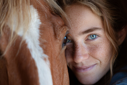 Close-up of a freckled girl smiling intimately while bonding face-to-face with a horse, showcasing connection and trust. - Powered by Adobe