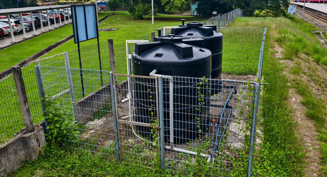 Two large black polyethylene water tanks,  for a rainwater harvesting system. These tanks are designed to collect and store rainwater for various uses. 