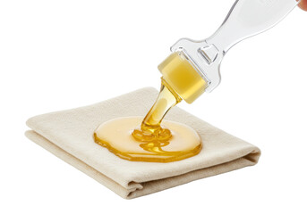 Isolated honey pouring from dipper onto folded napkin for skin care or food preparation
