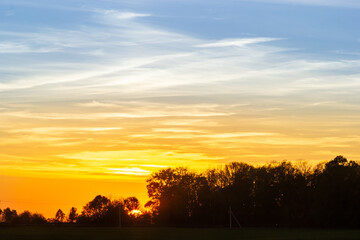 Stunning sunset over a tranquil landscape with vibrant colors and silhouettes of trees in the distance
