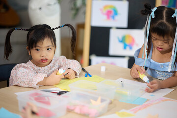 Girl with down syndrome diligently create art projects at a table, focusing on their creative tasks