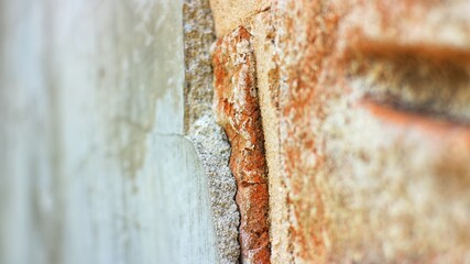 Cracked plaster and exposed brick edge, rough masonry wall texture close-up