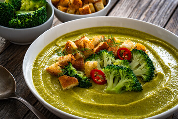 Garnished cream broccoli soup on wooden table	