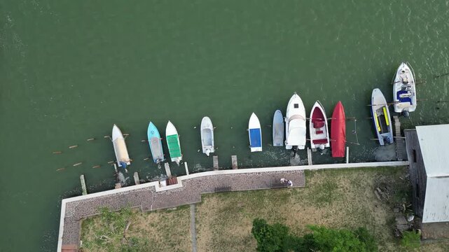 Aerial drone view of many boats moored along the shore of Burano island in the Venice lagoon, Italy.
