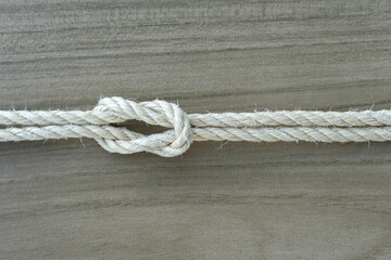 Close-up of a tied rope knot on light wood background, symbolizing trust, stability, connection, and teamwork. Ideal for conceptual visuals in business, nature, or cooperation themes.