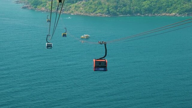 Aerial view of cable car gondola gliding over lush green island hills and turquoise sea. Longest Hon Thom cable car ride on Phu Quoc island, Vietnam. Modern tourism technology and eco transport