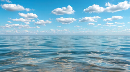 Obraz premium Serene ocean water reflects soft clouds under bright blue sky, creating tranquil atmosphere