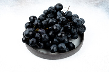 A bunch of black grapes on a white background. Fresh and juicy grapes.