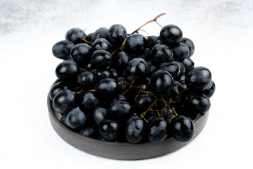 A bunch of black grapes on a white background. Fresh and juicy grapes.